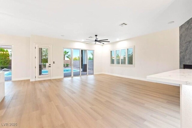 unfurnished living room with light wood-style flooring, plenty of natural light, a ceiling fan, baseboards, and recessed lighting