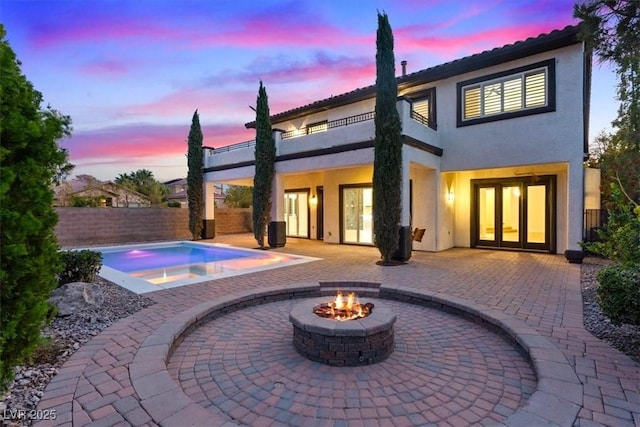 back of property with french doors, a fire pit, stucco siding, and a patio