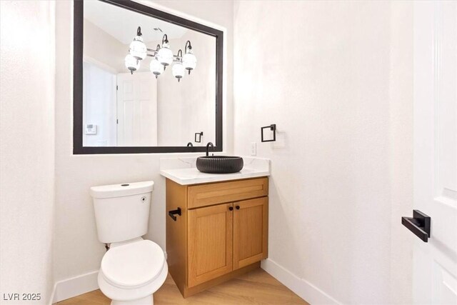 bathroom with baseboards, wood finished floors, toilet, and vanity