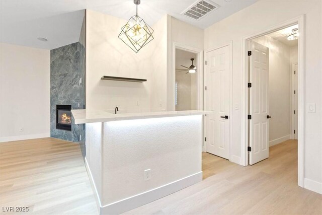 bathroom featuring wood finished floors, a tiled fireplace, baseboards, and ceiling fan