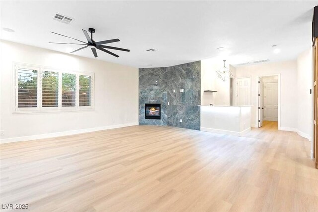 unfurnished living room with ceiling fan, baseboards, light wood-type flooring, and a fireplace