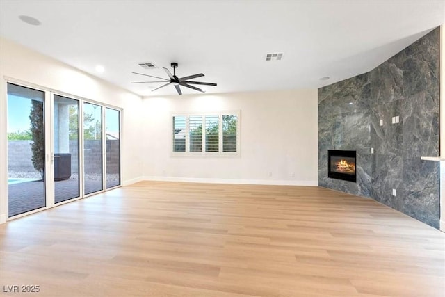 unfurnished living room featuring healthy amount of natural light, light wood-type flooring, baseboards, a tile fireplace, and recessed lighting