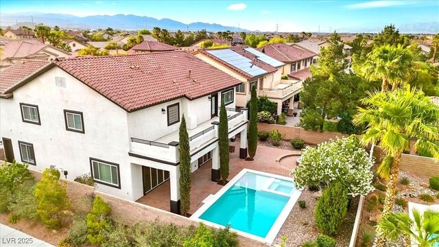 rear view of property with a residential view, a tile roof, a balcony, stucco siding, and a mountain view