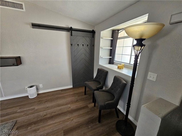 sitting room with vaulted ceiling, wood finished floors, a barn door, and baseboards