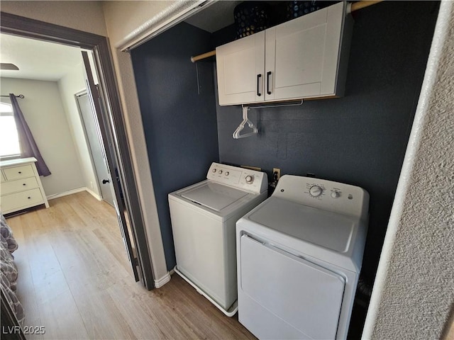 clothes washing area featuring washer and dryer, light wood finished floors, cabinet space, and baseboards