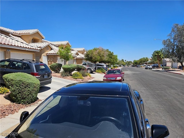 view of asphalt road featuring sidewalks, street lights, a residential view, and curbs