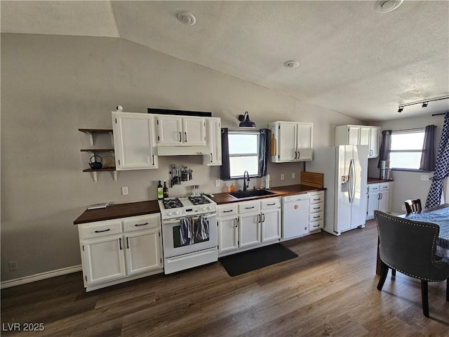 kitchen with white appliances, a sink, vaulted ceiling, a textured ceiling, and white cabinetry