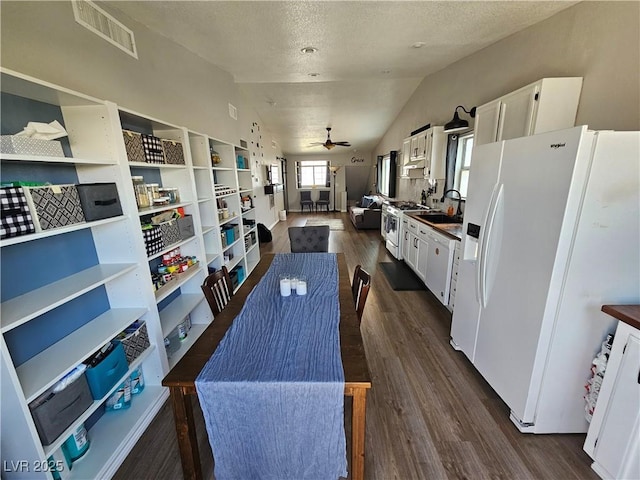kitchen with white appliances, a sink, ceiling fan, dark wood-style flooring, and white cabinets