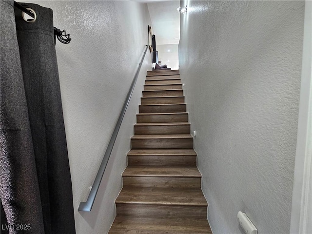 staircase featuring a textured wall and wood finished floors