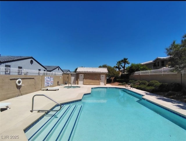 community pool featuring a fenced backyard, a hot tub, and a patio area