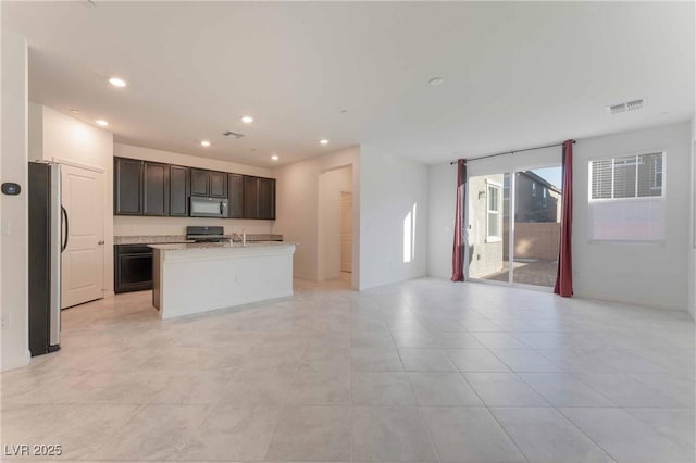 2824 Mozia Ct, Henderson, NV 89044 - kitchen with black microwave, freestanding refrigerator, range with gas cooktop, open floor plan, and light countertops