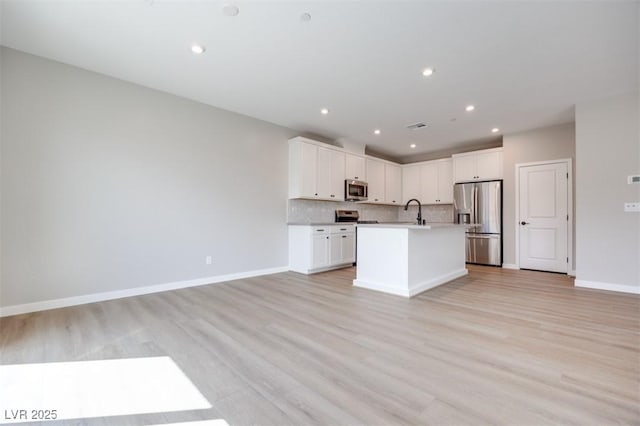 kitchen with stainless steel appliances, open floor plan, a sink, an island with sink, and recessed lighting