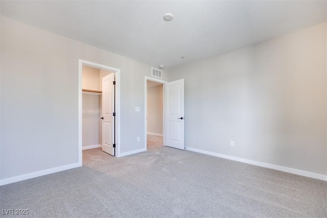 unfurnished bedroom featuring light colored carpet, a spacious closet, baseboards, and a closet