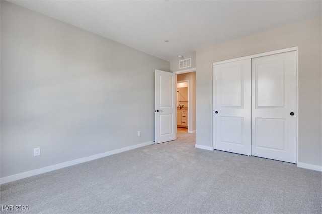 unfurnished bedroom with baseboards, light carpet, and a closet