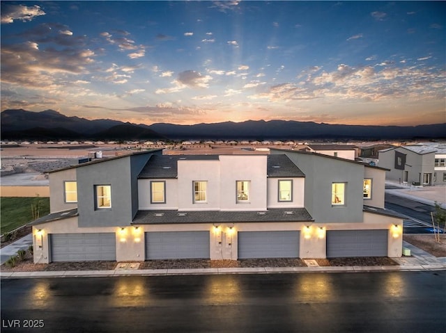 multi unit property featuring stucco siding, an attached garage, and a mountain view