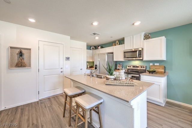 kitchen with appliances with stainless steel finishes, light wood-style floors, white cabinets, and recessed lighting