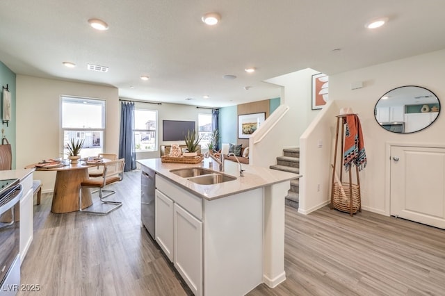 kitchen featuring a sink, light wood-style floors, recessed lighting, appliances with stainless steel finishes, and a center island with sink
