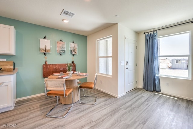 dining room featuring healthy amount of natural light, light wood-type flooring, and baseboards