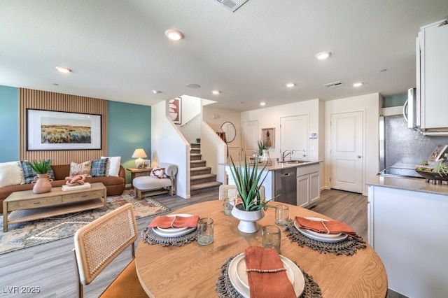 dining room with wood finished floors, stairs, and recessed lighting