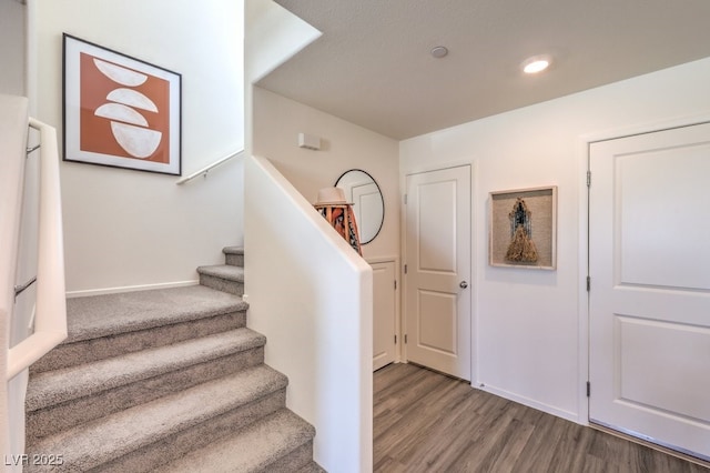 staircase with wood finished floors, recessed lighting, and baseboards