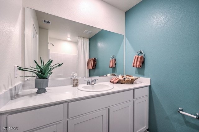 bathroom with a shower, a textured wall, and vanity
