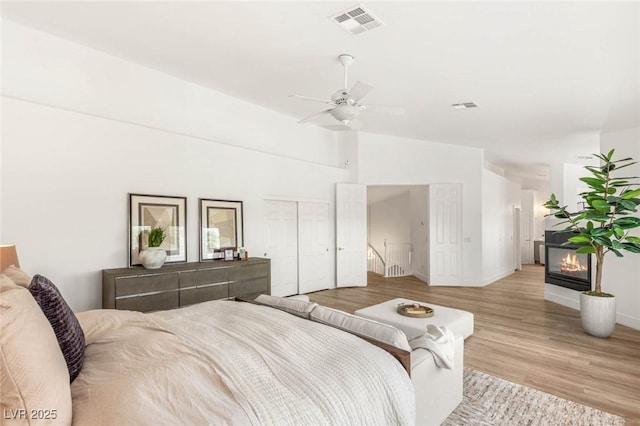 9615 Sedona Hills Ct, Las Vegas, NV 89147 - bedroom with light wood-style floors, a glass covered fireplace, ceiling fan, baseboards, and a closet