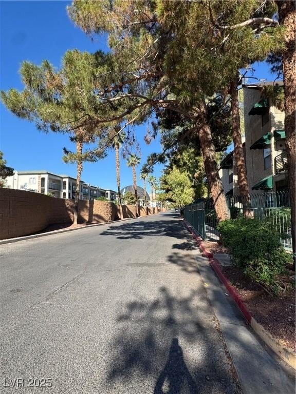 view of asphalt street featuring curbs and a residential view