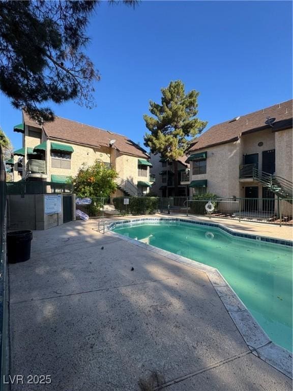 community pool with fence and a patio