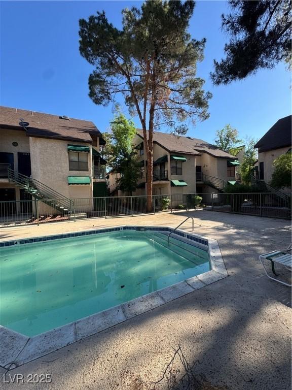 view of swimming pool featuring fence and a residential view