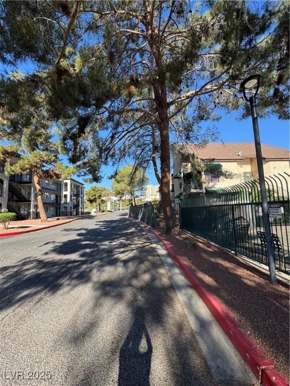 view of asphalt street featuring curbs, sidewalks, and a residential view