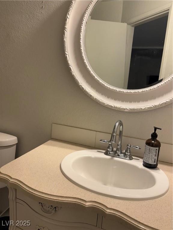 bathroom featuring vanity, toilet, and backsplash