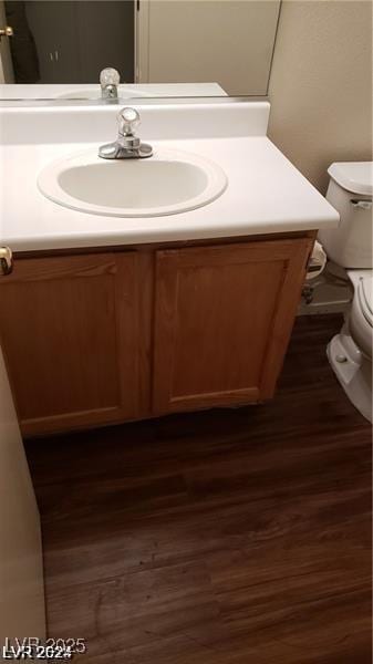 half bathroom featuring toilet, vanity, and wood finished floors