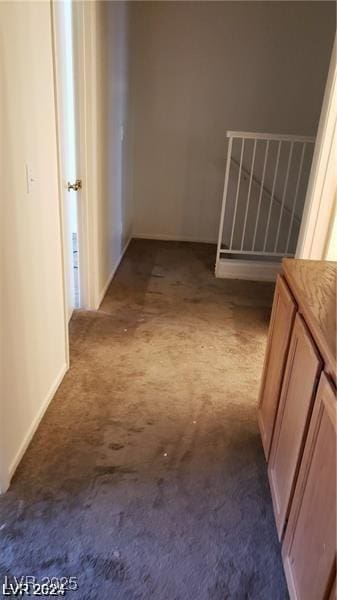 hall with dark colored carpet and baseboards