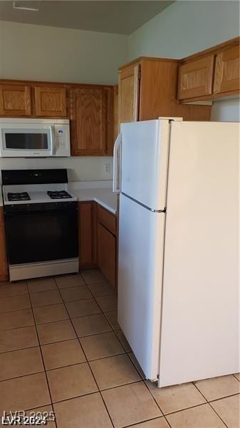 kitchen with white appliances, light tile patterned floors, light countertops, and brown cabinetry