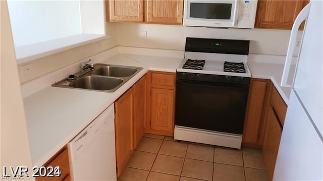 kitchen with white appliances, a sink, light countertops, and light tile patterned floors