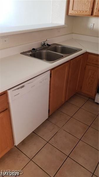 kitchen with white dishwasher, a sink, light countertops, and light tile patterned floors