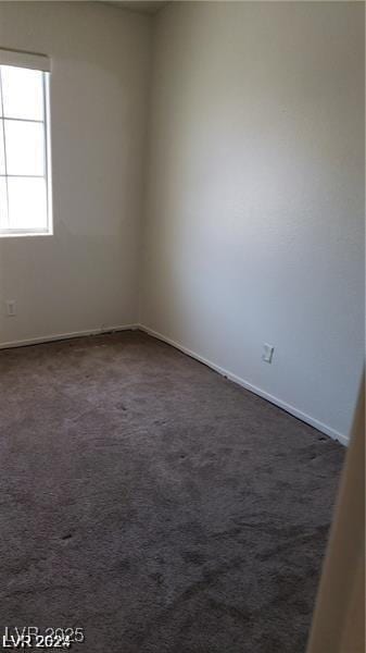 spare room with dark colored carpet and baseboards