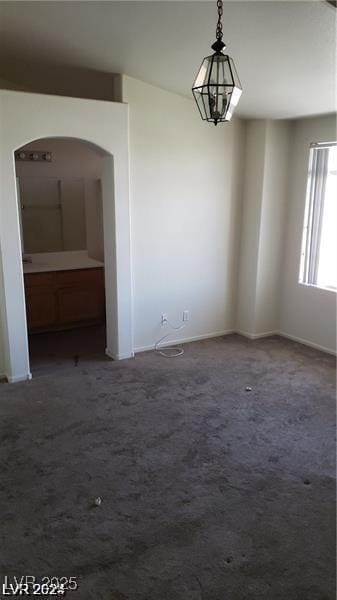 unfurnished room with carpet flooring, arched walkways, and baseboards