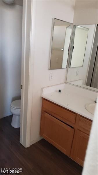 bathroom with wood finished floors, toilet, and vanity