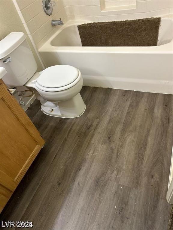 bathroom featuring toilet, wood finished floors, a bath, and a shower