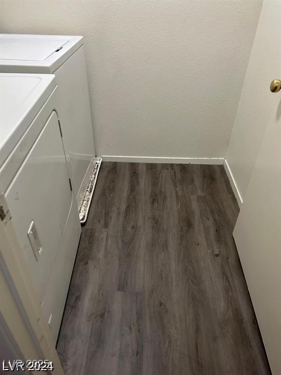 clothes washing area featuring washer and dryer, dark wood-type flooring, and baseboards