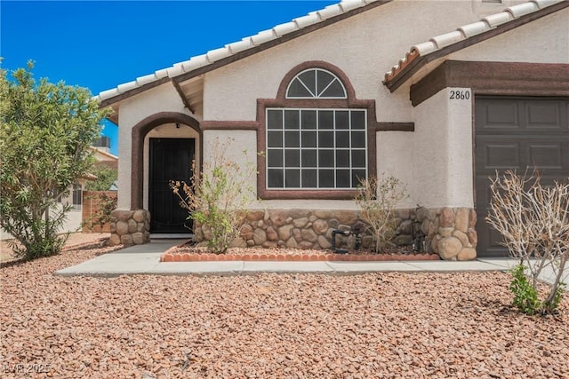 2860 Galena Peak Ln, Las Vegas, NV 89156 - property entrance featuring stucco siding, a tile roof, stone siding, and an attached garage