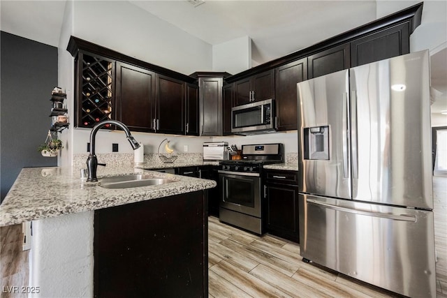 2860 Galena Peak Ln, Las Vegas, NV 89156 - kitchen featuring appliances with stainless steel finishes, a sink, a peninsula, and light stone countertops