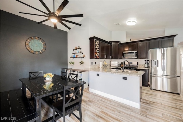 2860 Galena Peak Ln, Las Vegas, NV 89156 - kitchen featuring appliances with stainless steel finishes, ceiling fan, dark brown cabinets, light wood finished floors, and vaulted ceiling