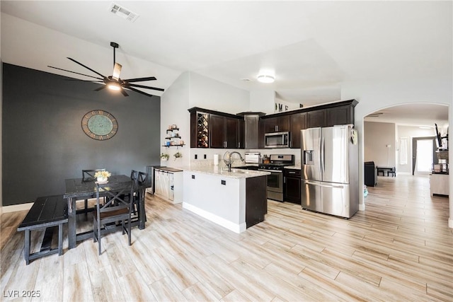2860 Galena Peak Ln, Las Vegas, NV 89156 - kitchen featuring stainless steel appliances, arched walkways, ceiling fan, vaulted ceiling, and dark brown cabinetry