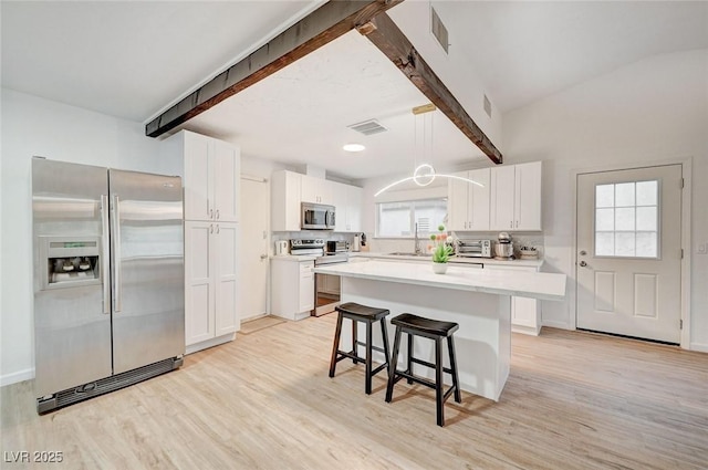 6771 Shelter Ln, Las Vegas, NV 89103 - kitchen with appliances with stainless steel finishes, beamed ceiling, light wood-type flooring, a breakfast bar area, and white cabinets