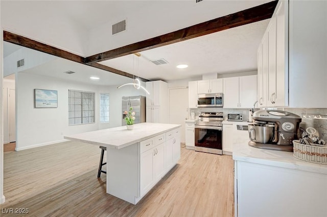 6771 Shelter Ln, Las Vegas, NV 89103 - kitchen with stainless steel appliances, beam ceiling, light wood finished floors, a center island, and white cabinets