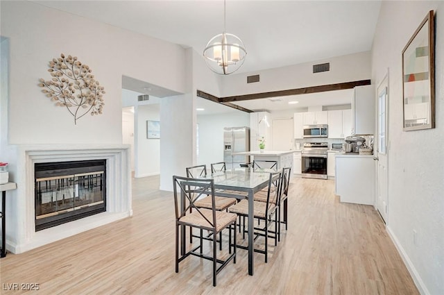 6771 Shelter Ln, Las Vegas, NV 89103 - dining space featuring light wood-style floors, a chandelier, baseboards, and a glass covered fireplace