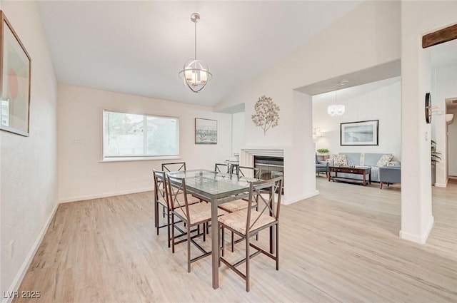 6771 Shelter Ln, Las Vegas, NV 89103 - dining area with a chandelier, light wood-style floors, a fireplace, baseboards, and high vaulted ceiling