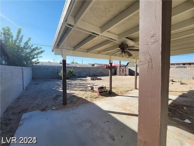 view of patio featuring a storage unit, a fenced backyard, an outbuilding, and ceiling fan